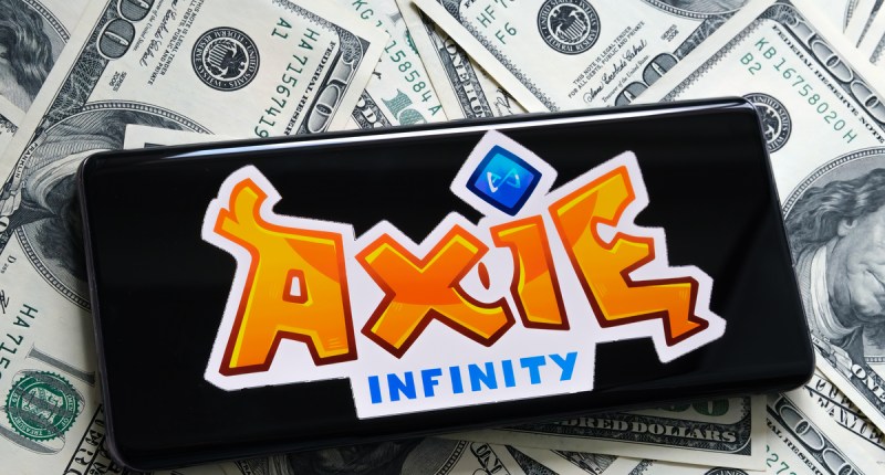 Smartphone sobre dólares mostra logo Axie Infinity