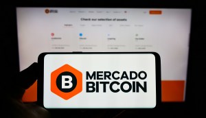 Telas de smartphone e computador sobrepostas mostram logo da corretora Mercado Bitcoin
