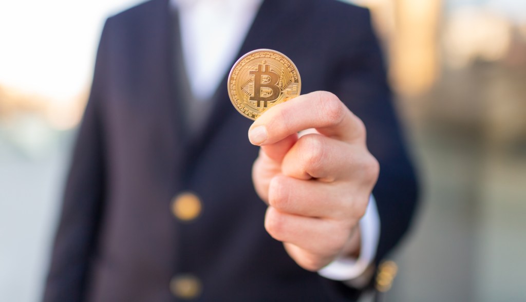 Moeda de bitcoin na mão de uma pessoa