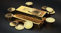 Barra de ouro envolto a várias moedas douradas de bitcoin