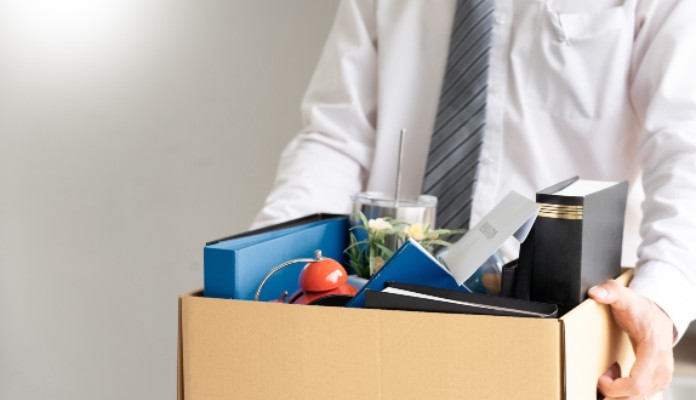 Homem carregando caixa de papelão com seus pertences