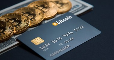 Moedas de bitcoin e cartão com o tema em cima de dólares sob mesa escura