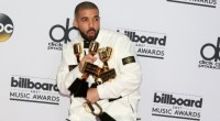 Drake, cantor e rapper, de terno branco segurando prêmios