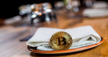 Moeda de bitcoin apoiada em um guardanapo dentro de um prato
