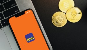 celular com logo do itau ao lado de criptomoedas e bitcoin