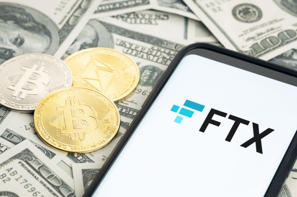 criptomoedas e celular com logo da FTX sobre notas de dinheiro