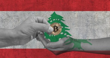 mãos trocando uma moeda de bitcoin BTC à frente de uma bandeira do Líbano