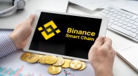 Uma perssoa segura um tablet com logo da Binance Smart Chain