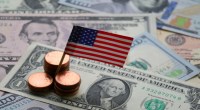 Monte de moedas seguram uma bandeira dos EUA em cima de dólares espalhados