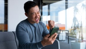 Homem comemora olhando para a tela do celular