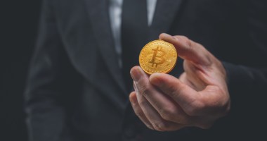 Mão estendendo uma moeda de bitcoin