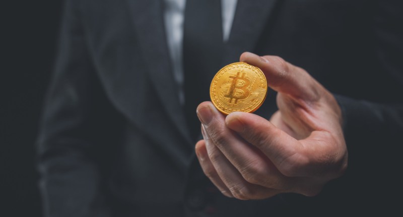 Mão estendendo uma moeda de bitcoin