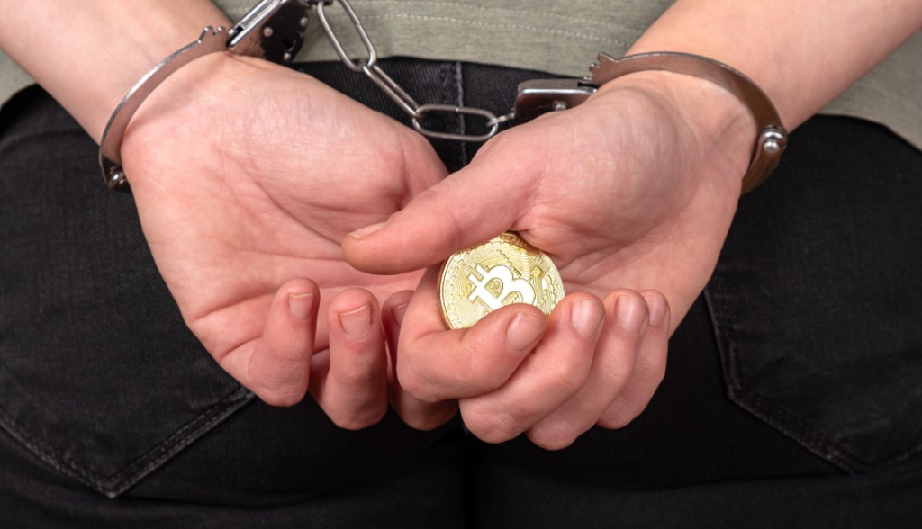 mãos algemadas seguram moeda de bitcoin