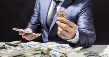 Homem sentado à mesa negociando bitcoin e dólar