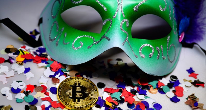 Moeda de bitcoin BTC entre confetes e máscara de carnaval