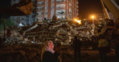 Mulher à frente do prédio destruído no terremoto do dia 6 de fevereiro de 2023 em Adana na Turquia