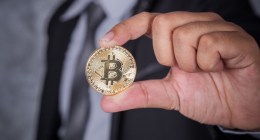 Mão segurando uma moeda de bitcoin