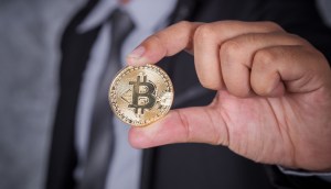 Mão segurando uma moeda de bitcoin