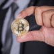 Mão segurando uma moeda de bitcoin