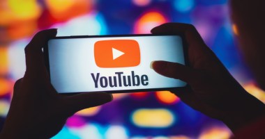 Smartphone mostra logotipo do Youtube de frente a fundo desfocado e colorido