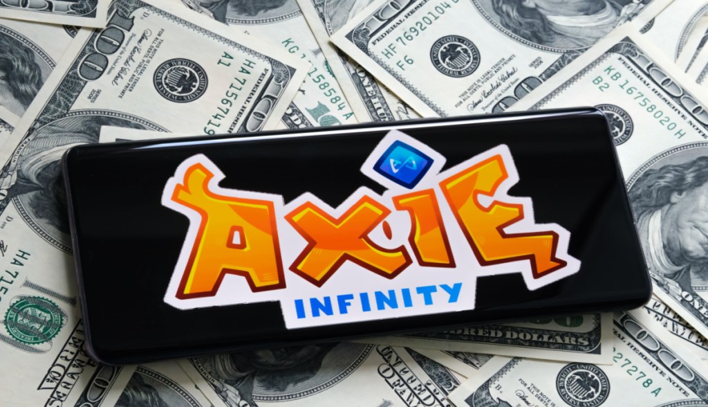Smartphone por cima de notas de dólares mostra logo da Axie Infinity