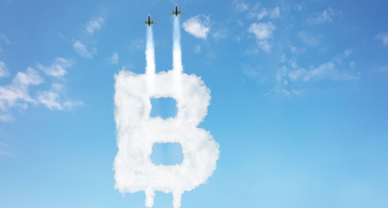 Dois aviões riscam com fumaça para cima o B de bitcoin