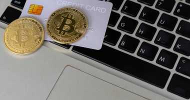 Moeda de bitcoin sob cartão de crédito sobrepostos em um teclado de laptop