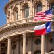 Bandeiras dos EUA e do estado do Texas no edifício do Capitólio em Austin