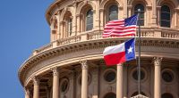 Bandeiras dos EUA e do estado do Texas no edifício do Capitólio em Austin