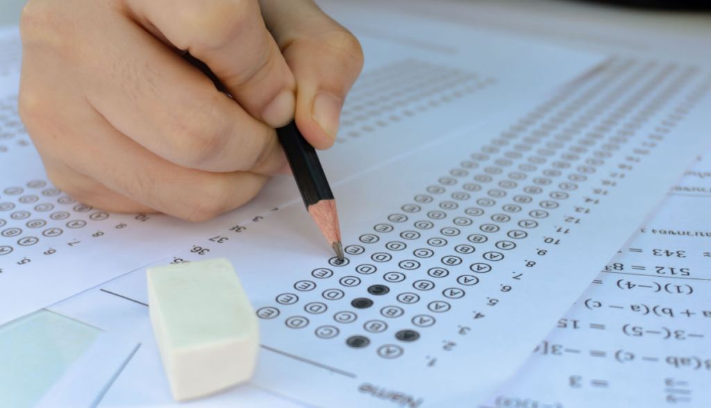 Close na mão de candidato preenche gabarito com lápis preto