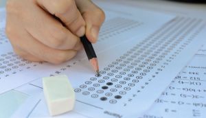 Close na mão de candidato preenche gabarito com lápis preto