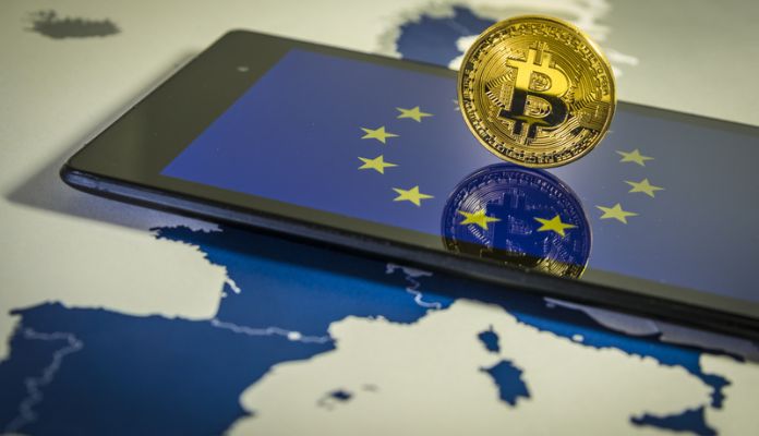 Moeda de Bitcoin em cima de celular com logo da UE União Europeia e em cima de mapa da Europa