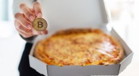 Pizza em uma mão moeda de bitcoin na outra