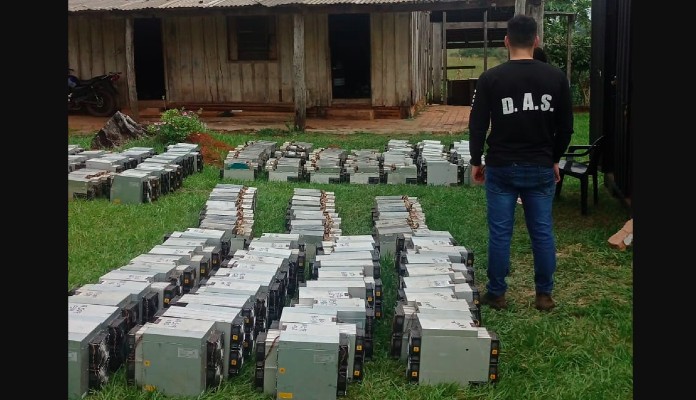 Agente da Polícia nacional do Paraguai observando centenas de máquinas de mineração em gramado
