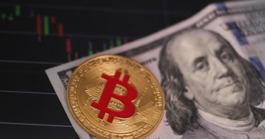 Moeda de Bitcoin sobre nota de dólar