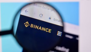 Tela de computador com logotipo da Binance e lente de aumento