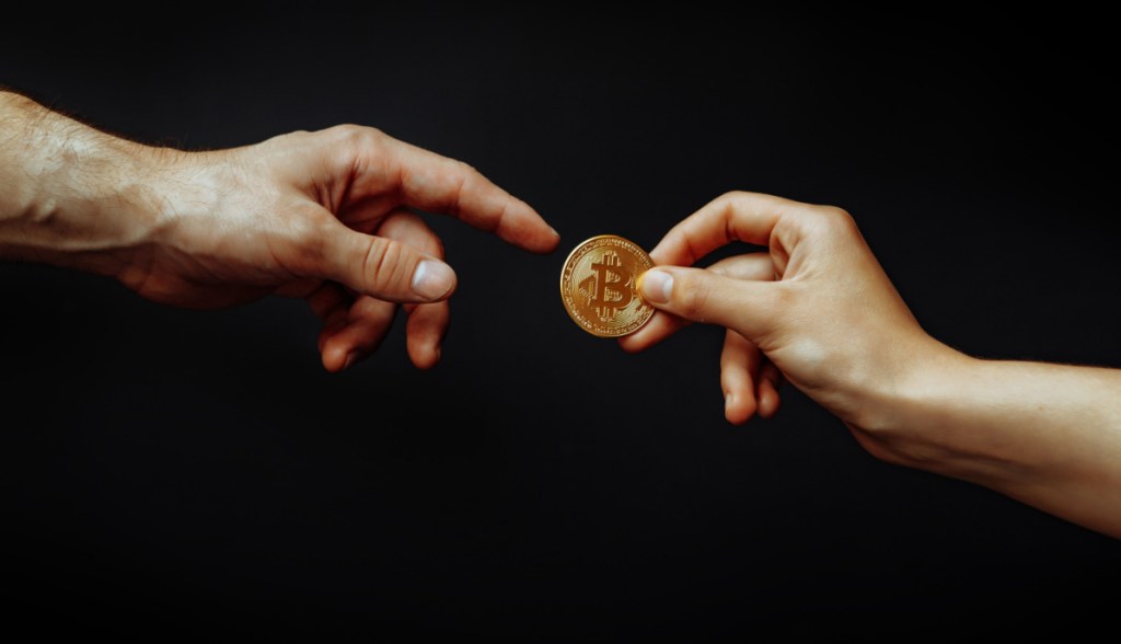 mãos trocando moedas de bitcoin