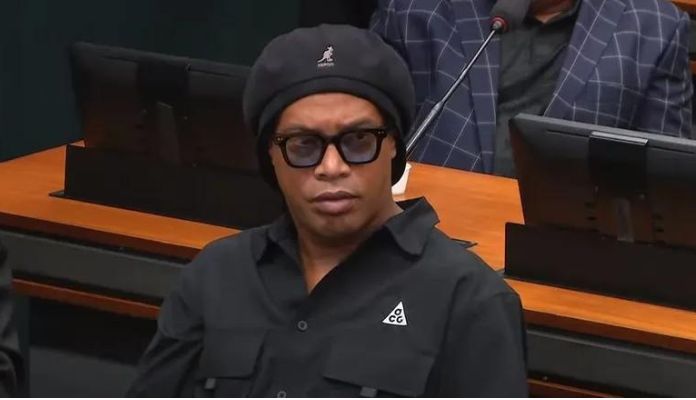 Ronaldinho Gaúcho de boina e camisa preta e óculos escuros na Câmara dos Deputados durante sessão da CPI das Pirâmides Financeiras