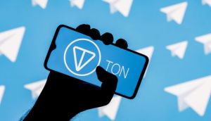 Mão segurando celular com logo da Toncoin e no fundo ícones do Telegram