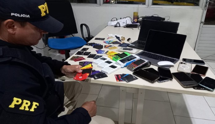 Agente da Polícia Rodoviária Federal (PRF) posa ao lado de dispositivos eletrônicos apreendidos