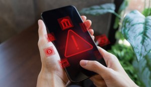 Uma pessoa segura um celular que mostra figuras grandes e vermelhas em formato triangular de alerta de vírus