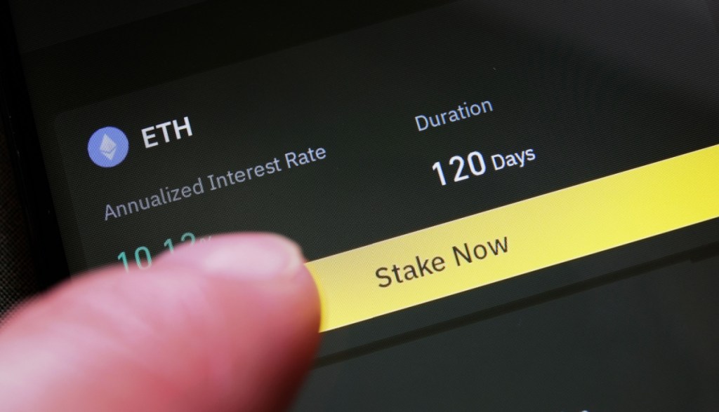 dedo sobre tela de celular em serviço de staking de criptomoeda