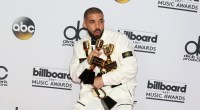 Drake, cantor e rapper, de terno branco segurando prêmios