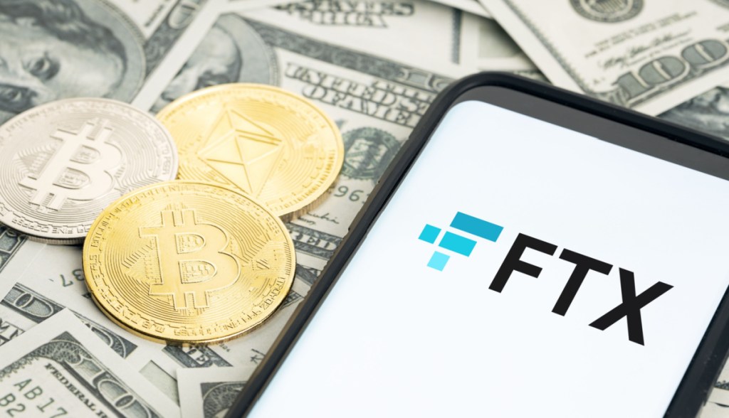 sob notas de dólares estão moedas de bitcoin, ethereum, ao lado de celular com logo FTX