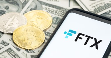 sob notas de dólares estão moedas de bitcoin, ethereum, ao lado de celular com logo FTX