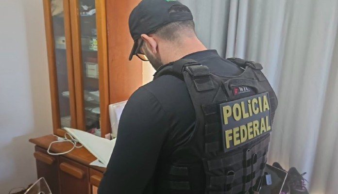 Agente da Polícia Federal dentro de residência fazendo anotações