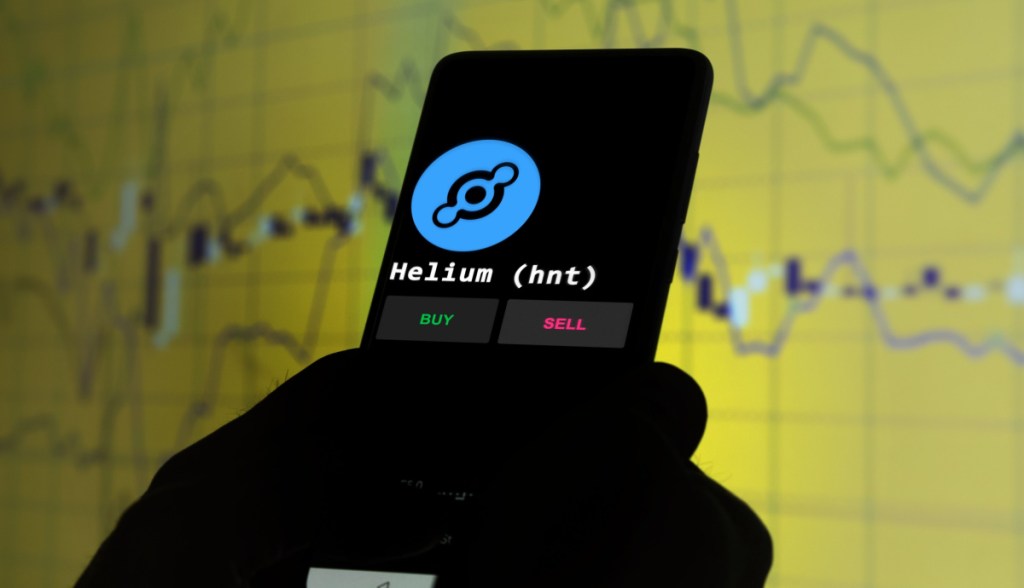 celular com logo da criptomoeda helium e grafico amarelo no fundo