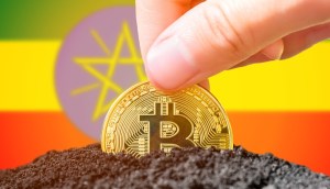 Moeda de Bitcoin semienterrada à frente de bandeira da Etiópia