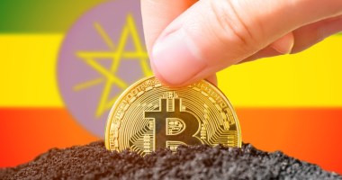 Moeda de Bitcoin semienterrada à frente de bandeira da Etiópia