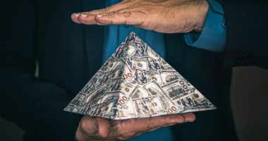 homem segura com duas mãos uma piramide de dinheiro